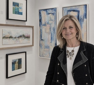 Laura Parker standing beside framed abstract artworks
